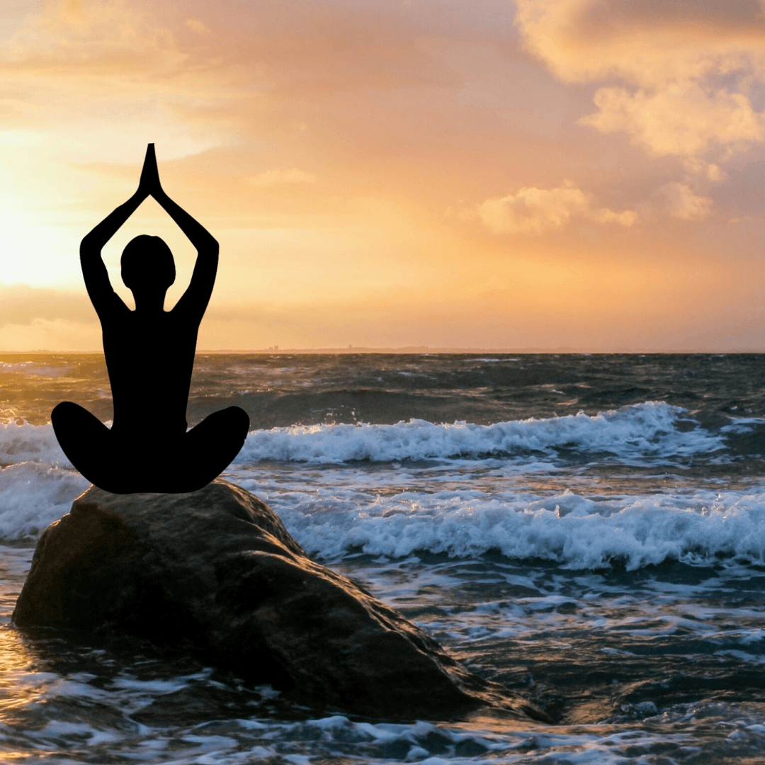Femme méditant assise en tailleur au bord de la mer, pratique de relaxation et pleine conscience.