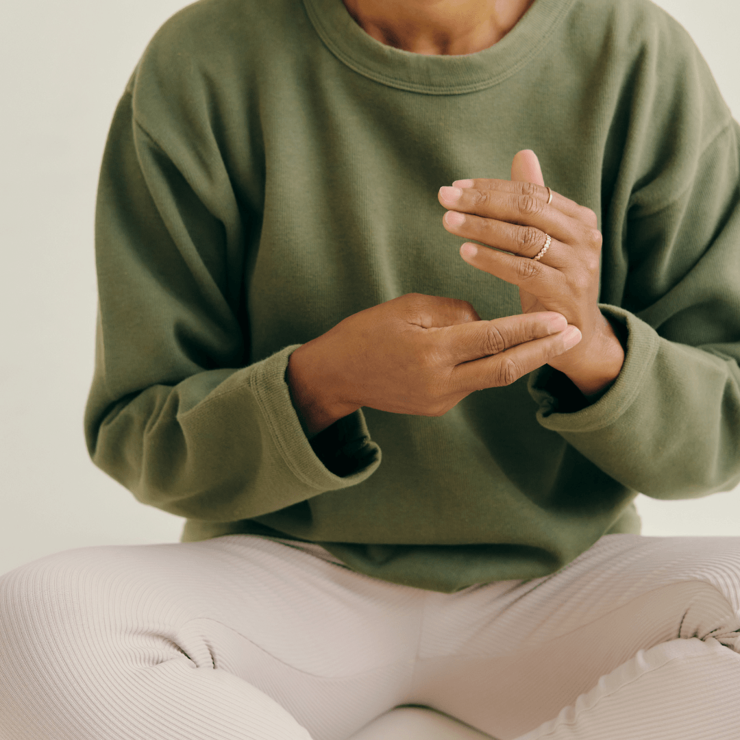Homme assis en tailleur, prenant son pouls, symbolisant la méditation et la conscience corporelle.