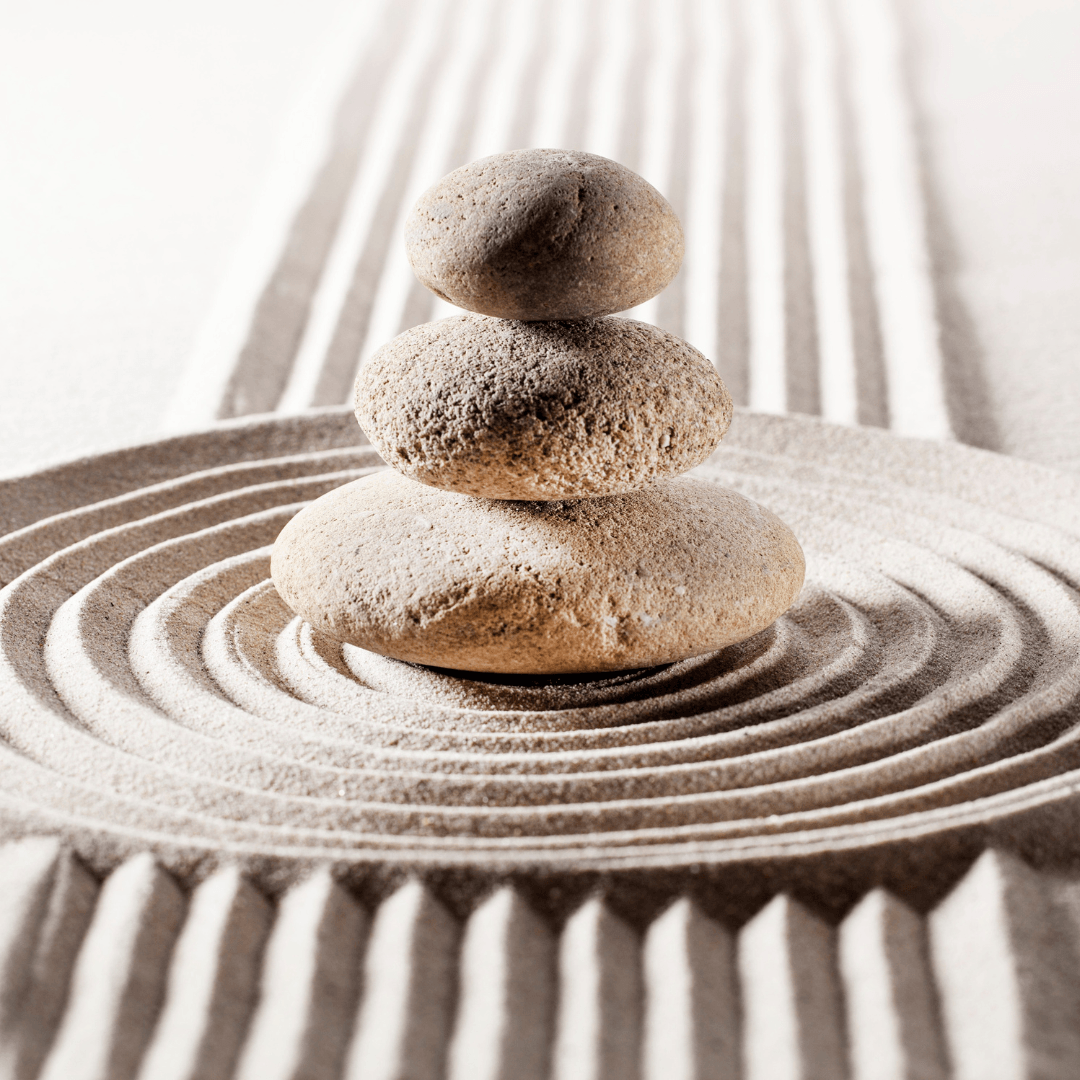 Galets empilés sur du sable, symbole de méditation, équilibre et pleine conscience.